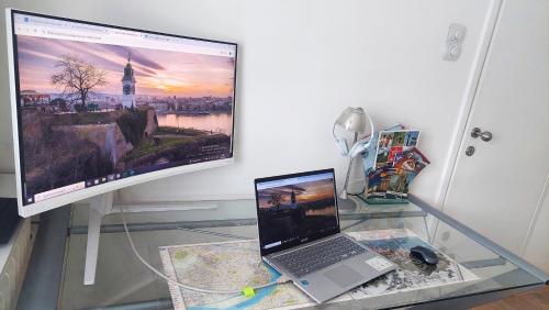 a glass table with a laptop and a large monitor at Apartment Spacious Liman in Novi Sad