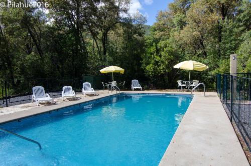 una piscina con sillas y sombrillas en Cabañas Pilahue, en Las Trancas