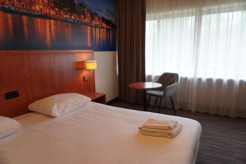a hotel room with a bed and a chair and a table at Westlake Hotels Amsterdam in Amsterdam