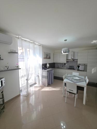 a white kitchen with a table and chairs in it at Casa Quattro Cannelli in Pozzuoli