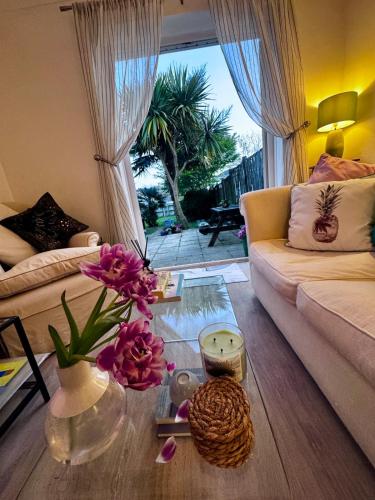 a living room with a couch and a table with flowers at Palm Valley Villa in Poole