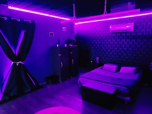 a bedroom with purple lights and a bed in a room at LIntemporel in Saint-Sornin