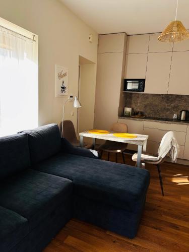 a living room with a blue couch and a table at Apartamentai Vetrungiu g 3 in Nida