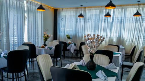 a restaurant with white tables and chairs and vases with flowers at Mamush Hotel in Ārba Minchʼ