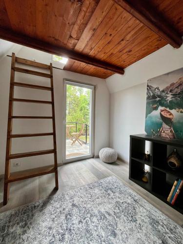 a room with a ladder and a large window at Hegyi Kuckó Vendégház - Forest Hideaway with Jacuzzi in Biatorbágy