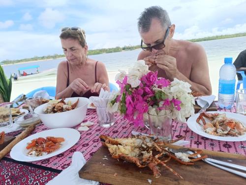 a man and a woman sitting at a table with food at Funzi Beach Resturant in Funzi