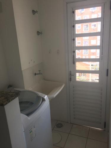 a bathroom with a washing machine and a window at Apartamento Jardim Bavieira in Canoas
