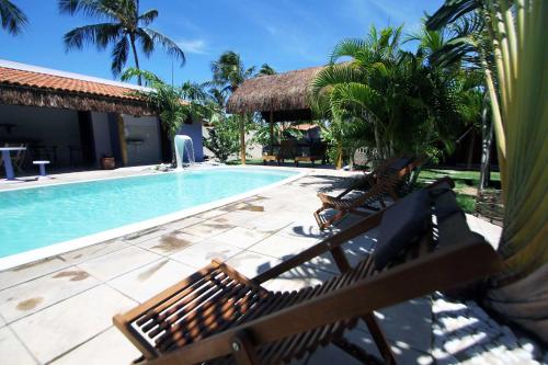 a swimming pool with two wooden benches next to a resort at Hawaii Flats in São Miguel do Gostoso