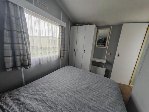 a bedroom with a bed and a window at 237 Sealands, 6 Birth caravan in Ingoldmells