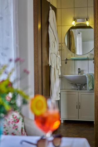 a bathroom with a sink and a glass of wine at Gasthof ALTE POST-Schwarzwald Plus gratis in Waldachtal