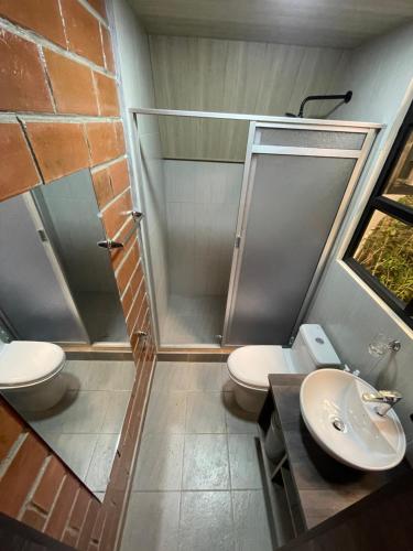 a bathroom with a shower and a toilet and a sink at Refugio de la niebla puyo glamping in Puyo
