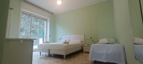 a white bedroom with two beds and a window at Penthouse in the historical center with sea view 5 minutes away,400mt, from main square in Amalfi