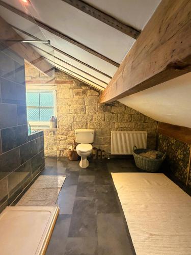 a bathroom with a toilet in a brick wall at Burnlee House Apartment in Holmfirth