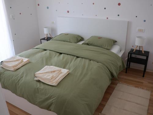 a bed with green sheets and two towels on it at Hiša Kovač in Velesovo