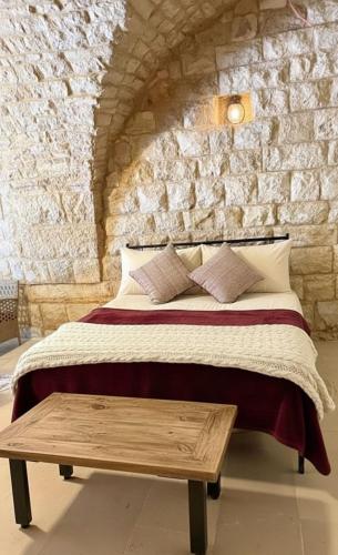 a bedroom with a bed and a wooden table at Bayt Broud in Gharīfah