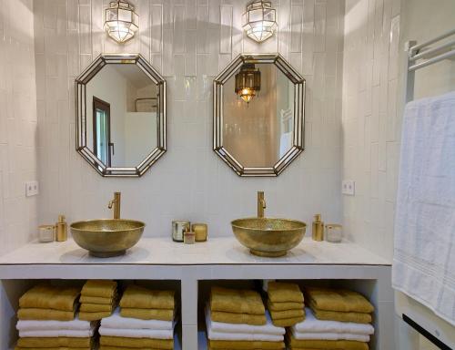two sinks in a bathroom with mirrors and towels at Villa Camilla in Comares
