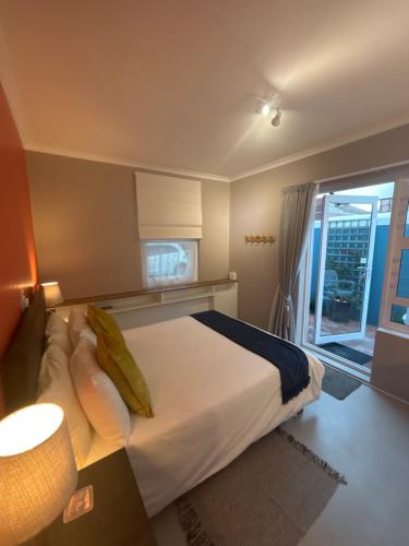 a bedroom with a large bed and a window at The Muizenberg Muse in Muizenberg