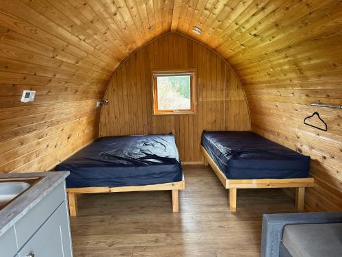 a bedroom with two beds in a wooden cabin at Rexes Hollow Camping in Yeovil Junction