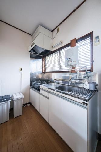 a kitchen with white cabinets and a sink at KEI HOUSE Yamato 202 in Yamato