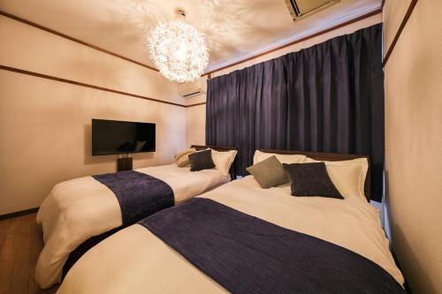 two beds in a hotel room with a chandelier at KEI HOUSE Yamato 202 in Yamato