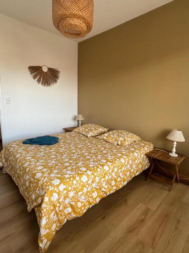 a bedroom with a bed with a comforter and two lamps at Appartement Bassin d' Arcachon in La Teste-de-Buch