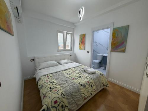a white bedroom with a bed and a bathroom at Grand House Apartment in Selitë e Vogël