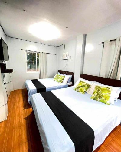 two beds in a hotel room with white and yellow pillows at Marias's Inn in Pooc