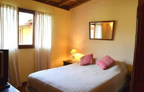 a bedroom with a bed with pink pillows and a window at Cabañas Alfar Sol y Mar in Mar del Plata