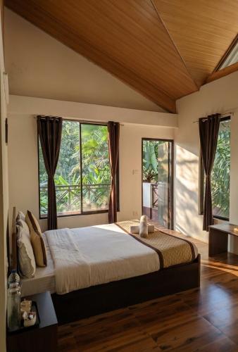 a bedroom with a large bed with windows at Kalimpong Bungalow in Kalimpong