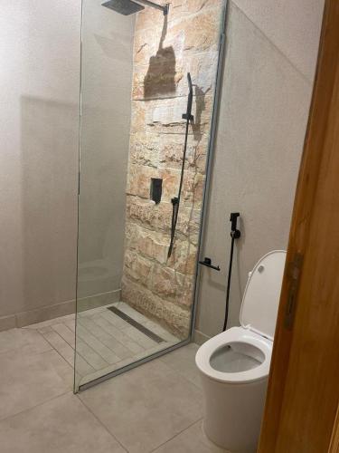 a bathroom with a toilet and a glass shower at Oasis Rest ae in Madīnat an Nahḑah