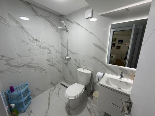 a white bathroom with a toilet and a sink at Grand House Apartment in Selitë e Vogël