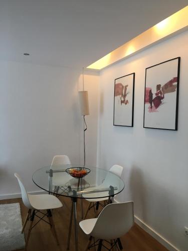 a dining room with a glass table and white chairs at Casa Pedra do Sal in Estoril