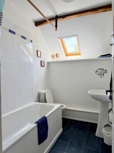 a bathroom with a tub and a toilet and a sink at La Cahudiere in Saint-Martin-Landelles