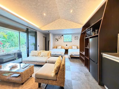 a living room with a couch and a bed at 奄美 Palm Tree Terrace in Ōkachi
