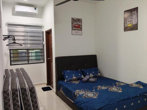 a bedroom with a bed with blue sheets and a window at Yashz Guest House in Port Dickson