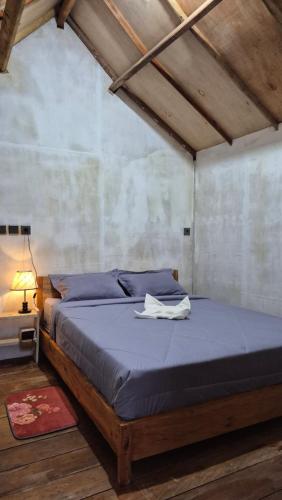 a bedroom with a bed with a blue comforter at Arsilahomestay in Tetebatu