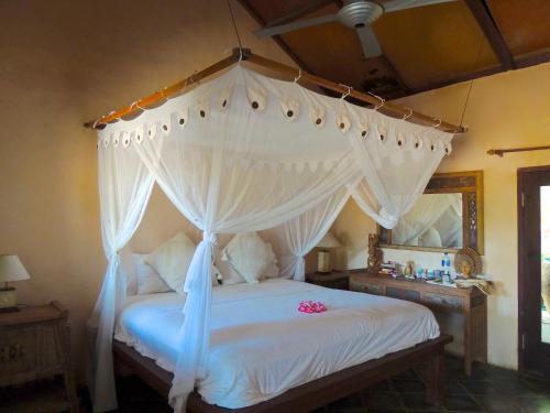 a bedroom with a white bed with a canopy at Villa Sedeoen in Nembrala