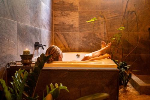 a woman laying in a bath tub in a bathroom at Samaya Wellness Lodge in Flores