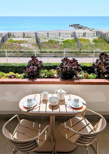 a table and chairs with a view of the ocean at Studio Vue mer, Piscine, Wifi, Climatisation, Parking privé, Terrasse 1ère ligne - La Coulée Douce in Frontignan