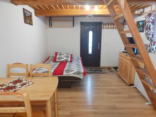 a room with a bed and a table and a staircase at Domek MIŚ Na Stoku in Tylicz