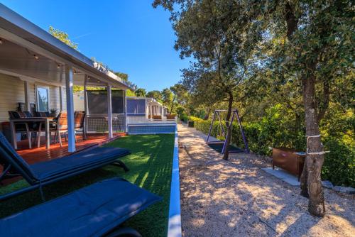 a house with a swing and a tree at ESTRADA MOBILE HoME in Biograd na Moru