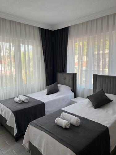 two beds in a hotel room with windows at Lilia Homes in Fethiye