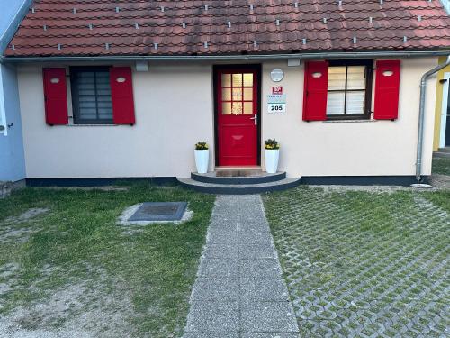 a white house with a red door and windows at La Hiška Čatež with Tickets - each guest gets 2 entries per day in Čatež ob Savi