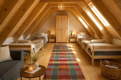a attic room with a bunch of beds and a rug at Rusínska chyža in Ulič