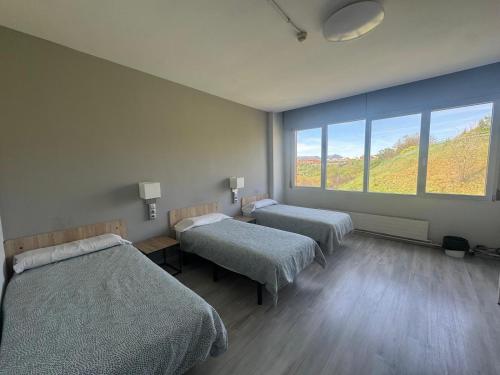 a room with two beds and a large window at Residencia Albergue Jaca in Jaca