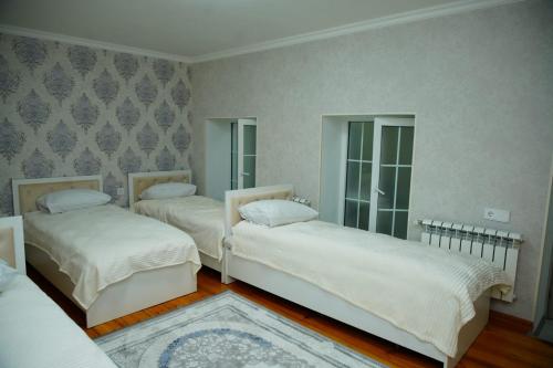 a bedroom with two beds with white sheets and a rug at Casa Serena Sheki in Sheki