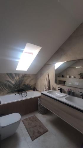 ein Badezimmer mit zwei Waschbecken, einer Badewanne und einer Toilette in der Unterkunft SIL House in Sîntandrei