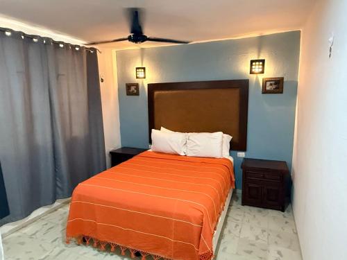 a bedroom with a bed with an orange blanket at Casita Escondida in Mérida