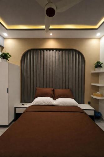 a bedroom with a large bed with a large headboard at Travellers Heaven in Karachi
