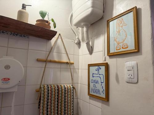 a bathroom with a toilet and pictures on the wall at Tilcara Mistica Hostel in Tilcara